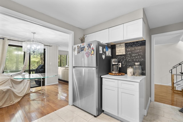 67 Woodside Cir Unit 67, Torrington, CT 06790 - kitchen with freestanding refrigerator, white cabinets, a chandelier, light countertops, and light wood-style flooring