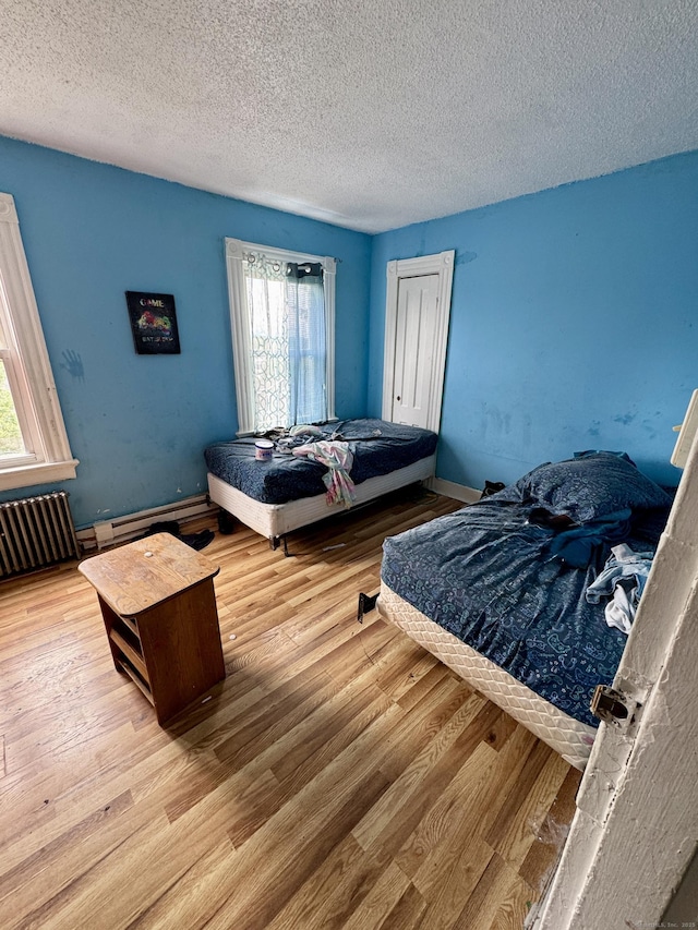 81 Easton Ave, Waterbury, CT 06704 - bedroom with wood finished floors, a textured ceiling, multiple windows, and radiator heating unit