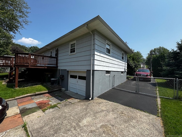 26 Oakleaf Dr, Waterbury, CT 06708 - view of side of home with a wooden deck, driveway, an attached garage, and a gate