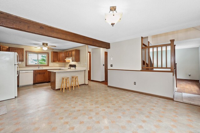 24 Cadbury Pl, Naugatuck, CT 06770 - kitchen with white appliances, light countertops, brown cabinets, beamed ceiling, and a peninsula