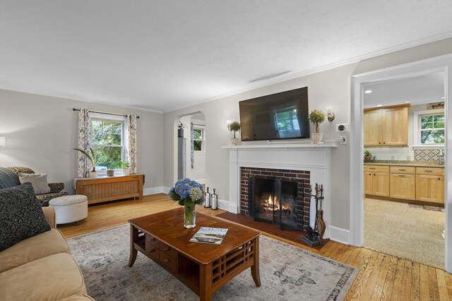 51 Carmel St, Hamden, CT 06518 - living area featuring light wood-style floors, a brick fireplace, healthy amount of natural light, arched walkways, and crown molding