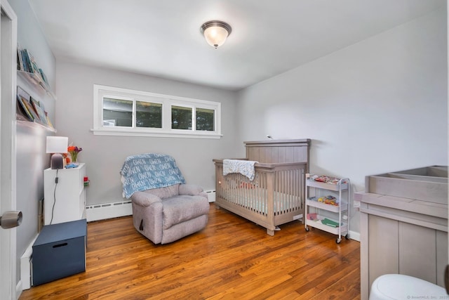 123 Geer Rd, Griswold, CT 06351 - bedroom featuring a baseboard heating unit, wood finished floors, and a crib