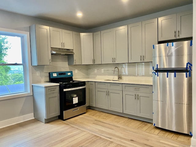 218 Charles St, Waterbury, CT 06708 - kitchen with freestanding refrigerator, gas range, under cabinet range hood, gray cabinetry, and light countertops