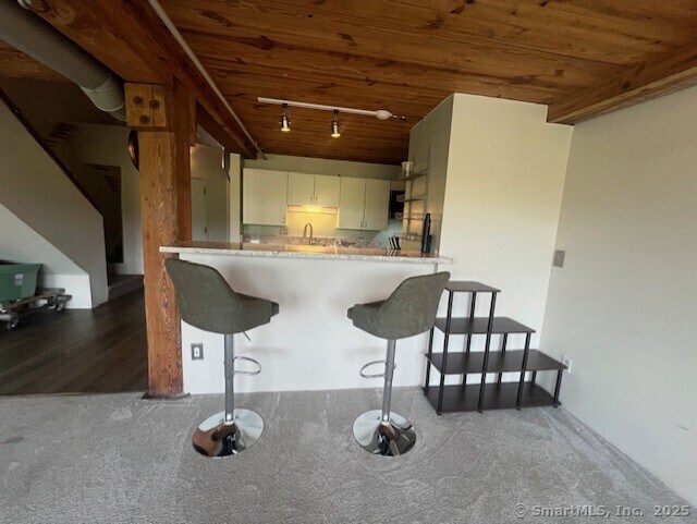 68 Thermos Ave Unit 206B, Norwich, CT 06360 - kitchen featuring wooden ceiling, rail lighting, a breakfast bar, carpet, and white cabinets