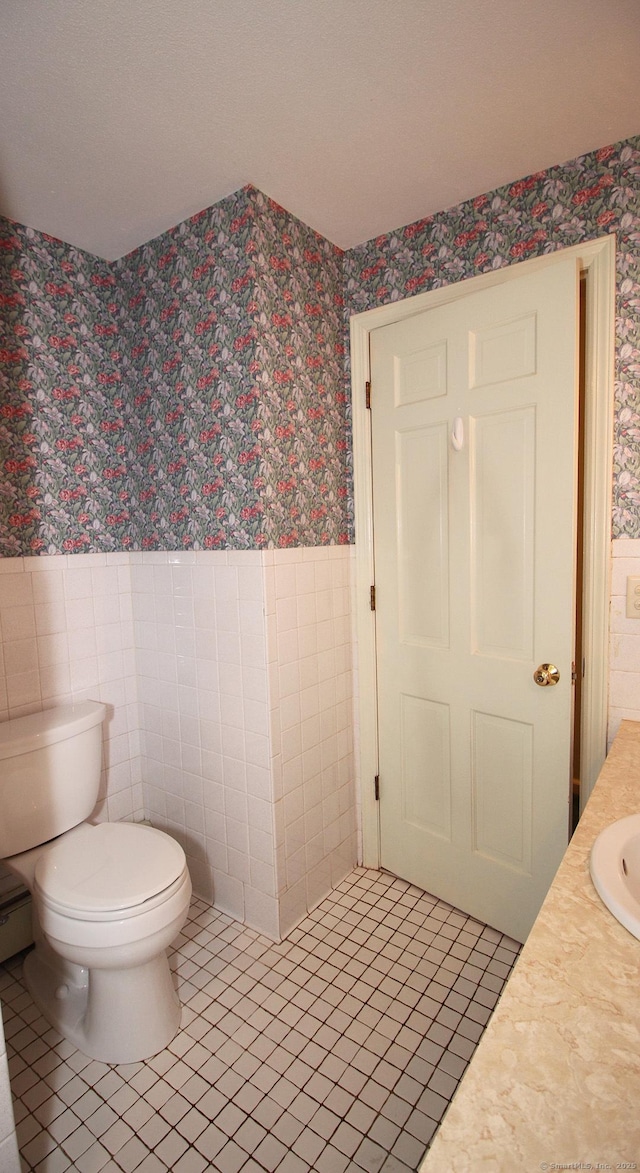 154 Sandy Ln, Meriden, CT 06450 - bathroom featuring wallpapered walls, wainscoting, tile walls, vanity, and tile patterned flooring