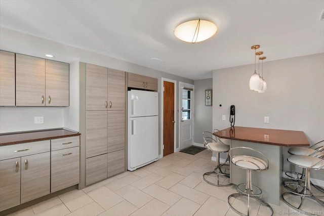 60 Ranch Rd, Milford, CT 06460 - kitchen with freestanding refrigerator, a kitchen breakfast bar, dark countertops, light tile patterned floors, and decorative light fixtures