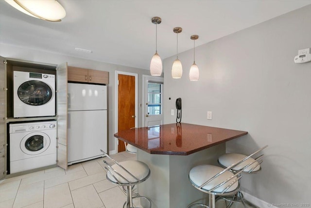 60 Ranch Rd, Milford, CT 06460 - kitchen featuring freestanding refrigerator, stacked washer / drying machine, a breakfast bar area, a peninsula, and light tile patterned flooring