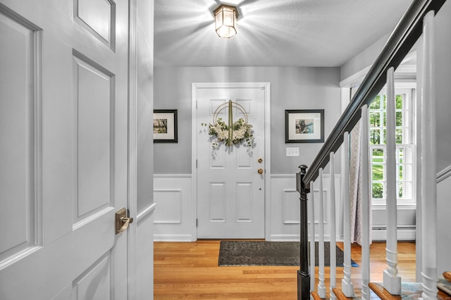 31 Country Way, Madison, CT 06443 - entryway featuring light wood finished floors, a baseboard radiator, stairway, wainscoting, and a textured ceiling