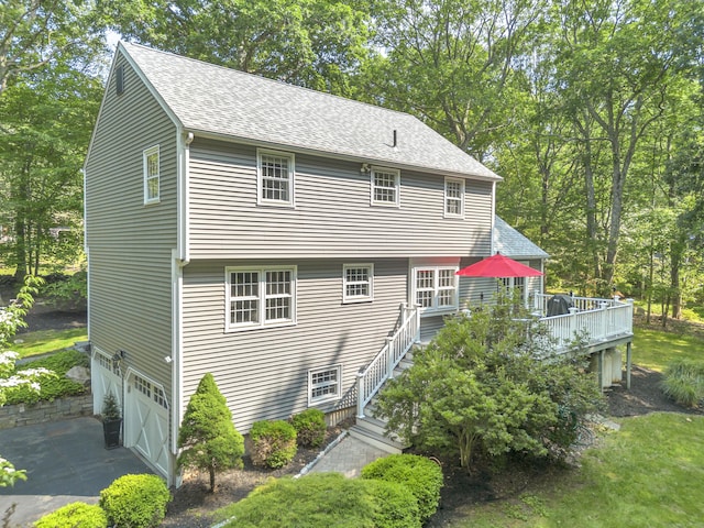 31 Country Way, Madison, CT 06443 - back of house featuring a garage, a shingled roof, a deck, driveway, and view of scattered trees