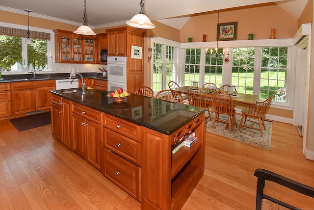 16 Brookfield Dr, Ellington, CT 06029 - kitchen with double oven, light wood-style flooring, brown cabinetry, an island with sink, and vaulted ceiling