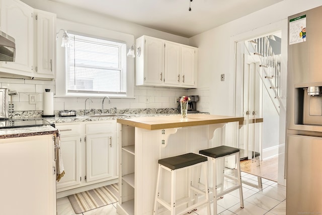 64 Mohawk Ave, Derby, CT 06418 - kitchen featuring backsplash, white cabinets, open shelves, and a breakfast bar area