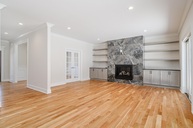 19 Ives Ct, Ridgefield, CT 06877 - unfurnished living room featuring light wood-type flooring, french doors, a multi sided fireplace, ornamental molding, and built in shelves
