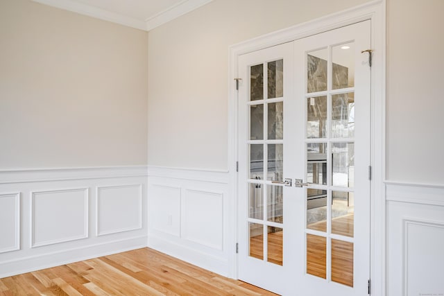 19 Ives Ct, Ridgefield, CT 06877 - empty room featuring crown molding, a decorative wall, light wood finished floors, french doors, and wainscoting