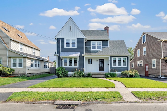 946 Wilcoxson Ave, Stratford, CT 06614 - view of front of house featuring board and batten siding, a front yard, roof with shingles, and a chimney