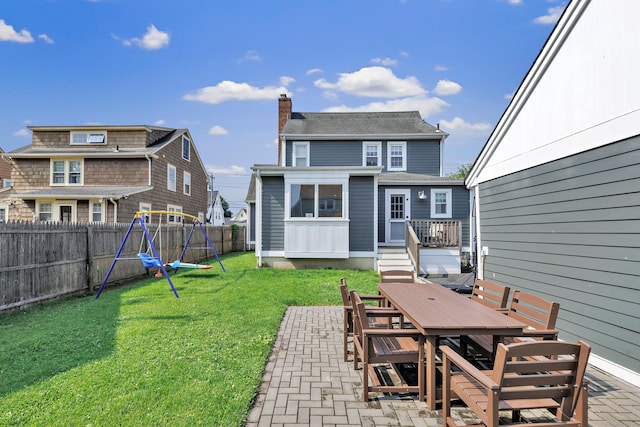 946 Wilcoxson Ave, Stratford, CT 06614 - back of property with outdoor dining space, a chimney, a fenced backyard, a patio area, and a playground