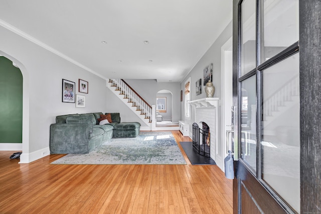 946 Wilcoxson Ave, Stratford, CT 06614 - living room with stairs, a fireplace, arched walkways, light wood finished floors, and crown molding