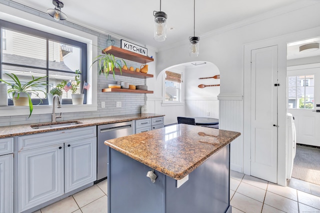 946 Wilcoxson Ave, Stratford, CT 06614 - kitchen with stainless steel dishwasher, light tile patterned floors, healthy amount of natural light, a kitchen island, and a wainscoted wall