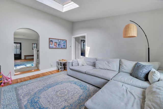 946 Wilcoxson Ave, Stratford, CT 06614 - living area featuring arched walkways, wood finished floors, a skylight, and vaulted ceiling