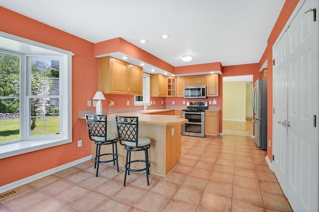 125 E Old Route 6, Hampton, CT 06247 - kitchen featuring appliances with stainless steel finishes, a peninsula, light countertops, a breakfast bar area, and light brown cabinetry