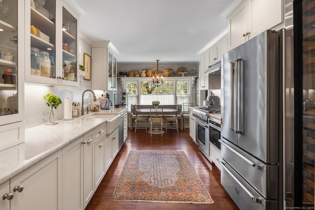 7 Morningside Ln, Westport, CT 06880 - kitchen featuring high end appliances, a chandelier, dark wood finished floors, white cabinets, and light stone countertops