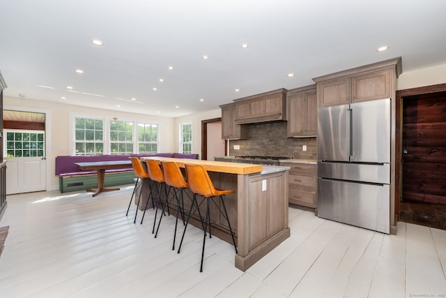 93 Northfield Rd, Litchfield, CT 06759 - kitchen featuring stainless steel fridge, a center island, light countertops, a kitchen bar, and decorative backsplash