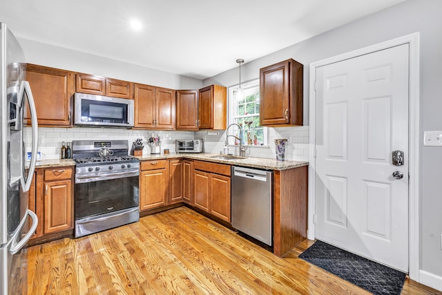 20 Oakland Ave Apt 3B, Danbury, CT 06810 - kitchen with appliances with stainless steel finishes, light wood-style floors, tasteful backsplash, light stone countertops, and brown cabinets