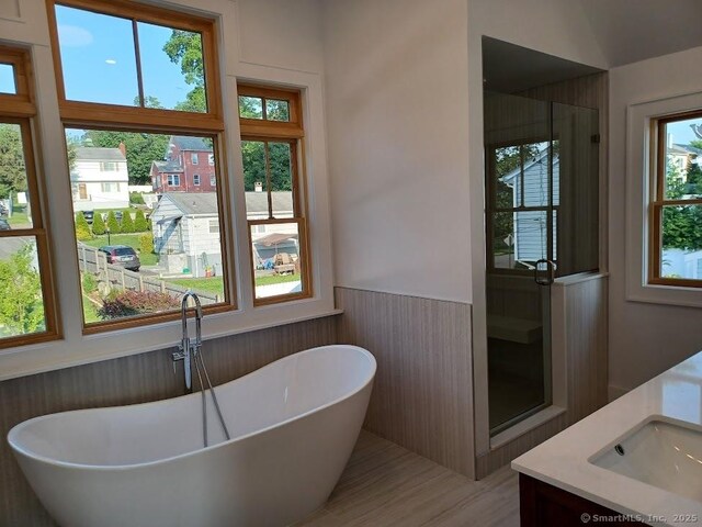 105 Houston Ter, Stamford, CT 06902 - bathroom with wainscoting, double vanity, a freestanding bath, wood finished floors, and wooden walls