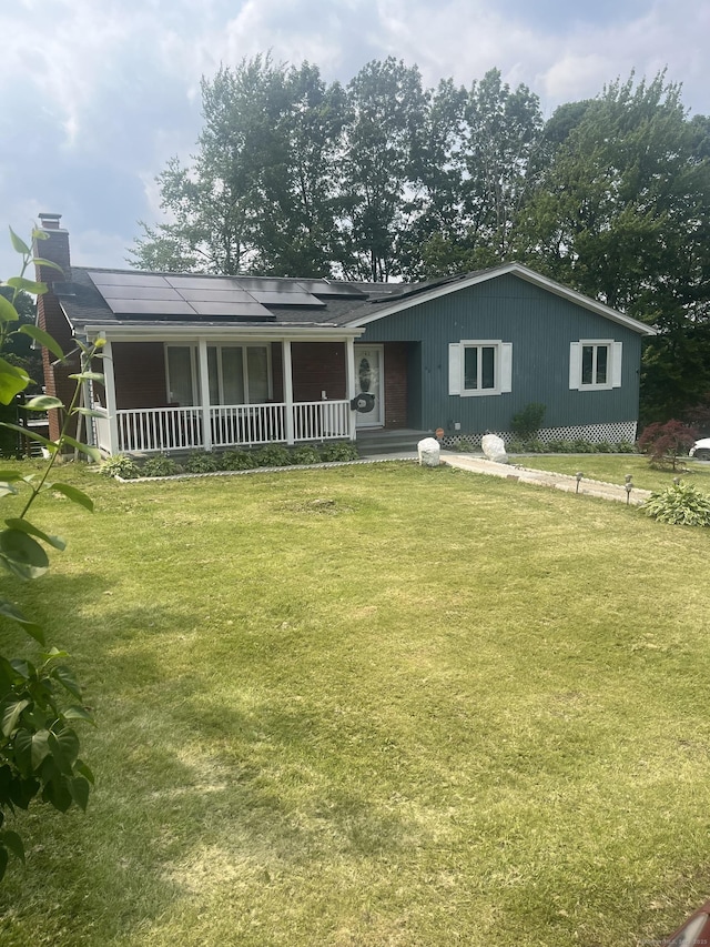 62 Haddad Rd, Waterbury, CT 06708 - view of front facade with covered porch, a front yard, solar panels, and a chimney