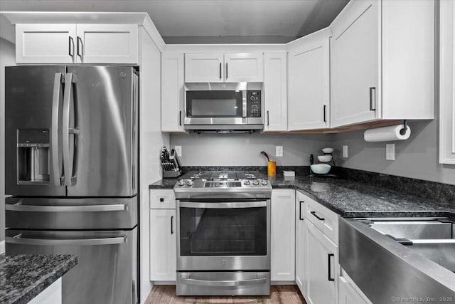379 Tripp Hollow Rd, Brooklyn, CT 06234 - kitchen with appliances with stainless steel finishes, white cabinets, light wood-style floors, and dark stone counters