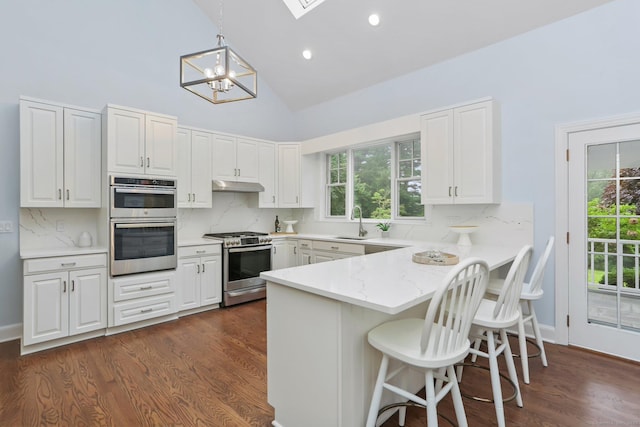 2787 Redding Rd, Fairfield, CT 06824 - kitchen with appliances with stainless steel finishes, a peninsula, under cabinet range hood, a chandelier, and a kitchen bar