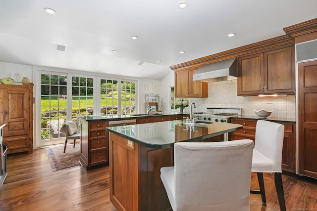 216 Hillspoint Rd, Westport, CT 06880 - kitchen with wall chimney exhaust hood, a kitchen island with sink, dark countertops, dark wood-style flooring, and recessed lighting