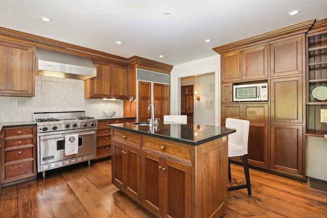216 Hillspoint Rd, Westport, CT 06880 - kitchen with premium appliances, wall chimney exhaust hood, dark countertops, dark wood finished floors, and recessed lighting