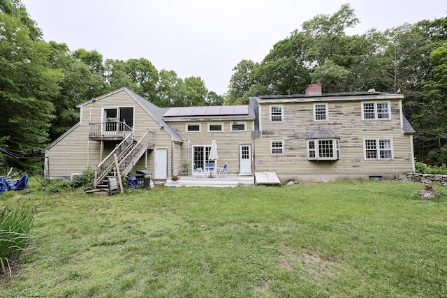 15 Harris Rd, Salem, CT 06420 - rear view of property with roof mounted solar panels, a deck, stairway, a lawn, and a chimney