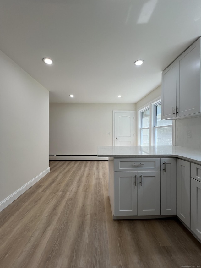 52 Sylvan St, Avon, CT 06001 - kitchen with wood finished floors, a peninsula, light countertops, a baseboard heating unit, and recessed lighting