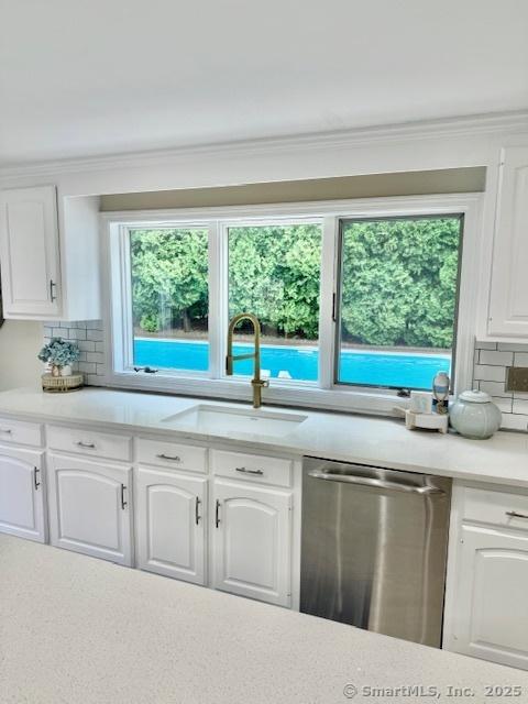 13 Charter Oak Dr, East Lyme, CT 06333 - kitchen featuring stainless steel dishwasher, tasteful backsplash, light countertops, white cabinets, and crown molding