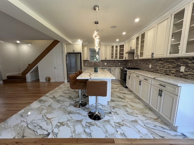 372 Oakland St, Manchester, CT 06042 - kitchen featuring appliances with stainless steel finishes, a breakfast bar, light stone countertops, backsplash, and a kitchen island
