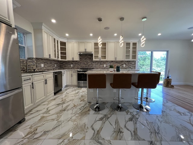 372 Oakland St, Manchester, CT 06042 - kitchen with appliances with stainless steel finishes, decorative backsplash, a center island, a kitchen bar, and recessed lighting