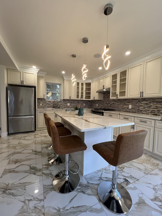 372 Oakland St, Manchester, CT 06042 - kitchen featuring freestanding refrigerator, decorative backsplash, a center island, light stone countertops, and a breakfast bar area