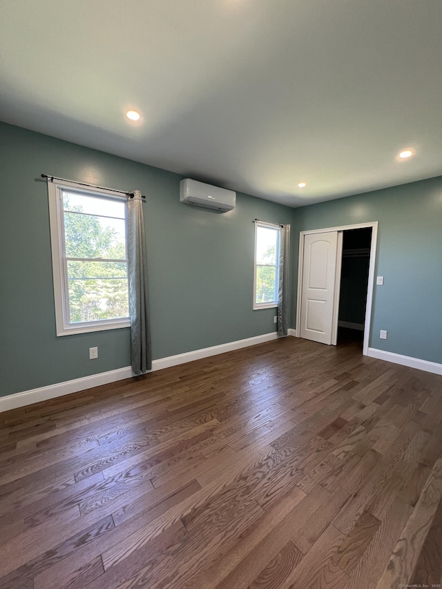 372 Oakland St, Manchester, CT 06042 - unfurnished room featuring a wall unit AC, dark wood-style floors, and recessed lighting