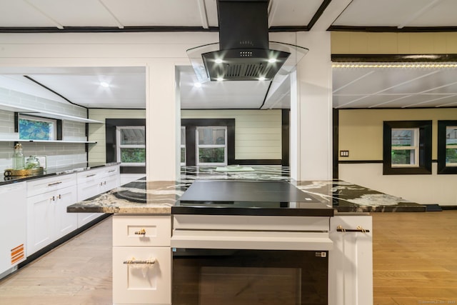486 Barlow St, Bristol, CT 06010 - kitchen featuring wall chimney exhaust hood, light wood-style floors, white cabinets, dark stone countertops, and wall oven