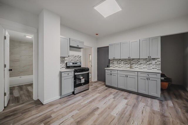 156 Waterville St, Waterbury, CT 06710 - kitchen featuring stainless steel gas range oven, gray cabinets, light countertops, tasteful backsplash, and light wood finished floors