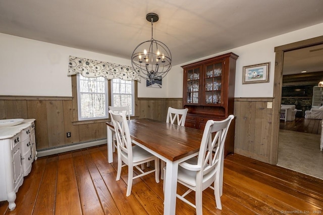 127 Skunk Misery Rd, Haddam, CT 06441 - dining area with a wainscoted wall, wooden walls, baseboard heating, wood-type flooring, and a chandelier