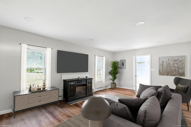971 New Litchfield St, Torrington, CT 06790 - living area featuring baseboard heating, wood finished floors, a glass covered fireplace, recessed lighting, and a baseboard radiator