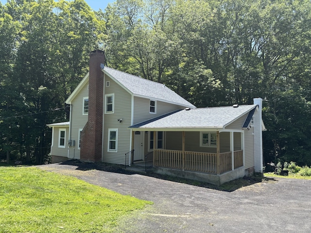 971 New Litchfield St, Torrington, CT 06790 - view of front of home with covered porch, a chimney, driveway, a front yard, and roof with shingles