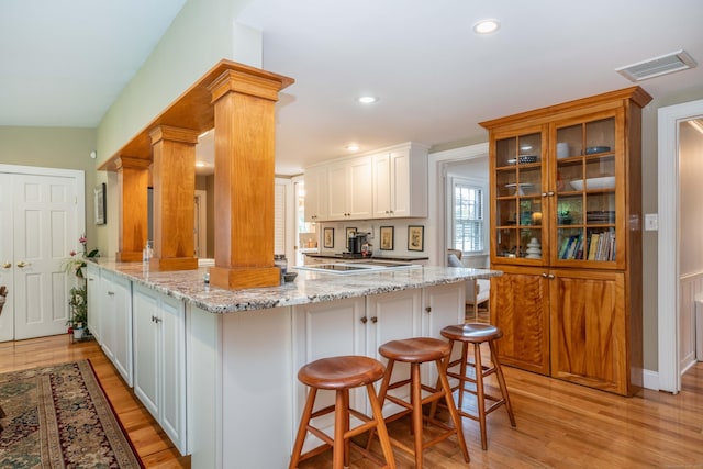 251 Ridgewood Rd, West Hartford, CT 06107 - kitchen featuring light wood-style floors, a peninsula, light stone countertops, a kitchen bar, and recessed lighting