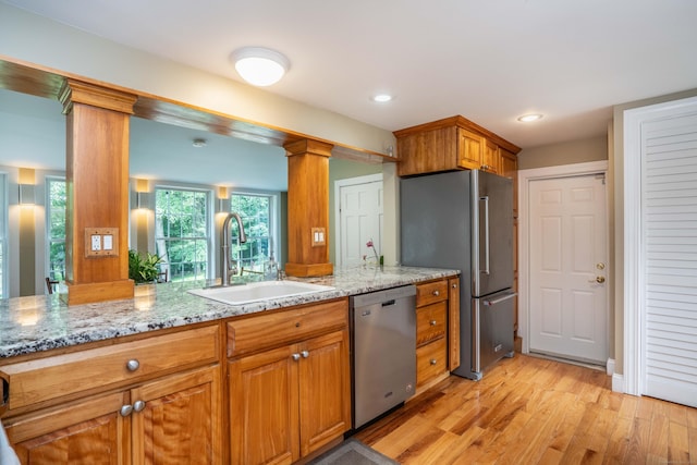 251 Ridgewood Rd, West Hartford, CT 06107 - kitchen with appliances with stainless steel finishes, decorative columns, brown cabinets, light wood finished floors, and light stone countertops