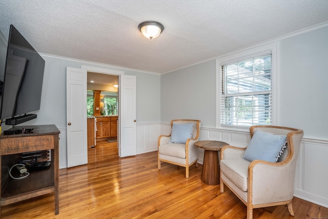 251 Ridgewood Rd, West Hartford, CT 06107 - sitting room with ornamental molding, a textured ceiling, light wood finished floors, plenty of natural light, and a wainscoted wall