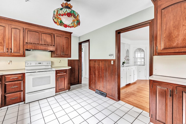 3 Wheeler Dr, Trumbull, CT 06611 - kitchen featuring white electric stove, light countertops, under cabinet range hood, wainscoting, and light tile patterned floors