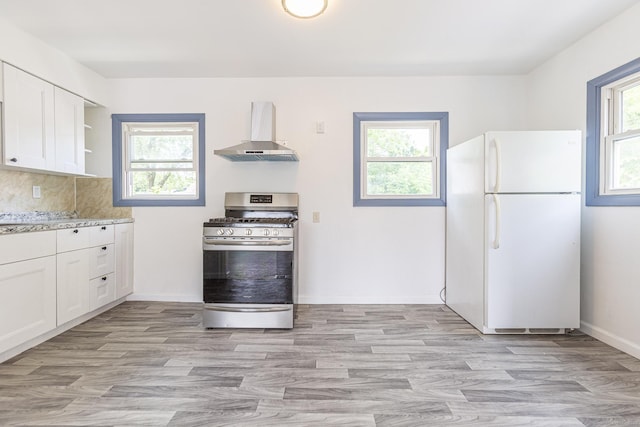 47 Manwaring Rd, Norwich, CT 06360 - kitchen featuring freestanding refrigerator, wall chimney range hood, stainless steel range with gas stovetop, and plenty of natural light