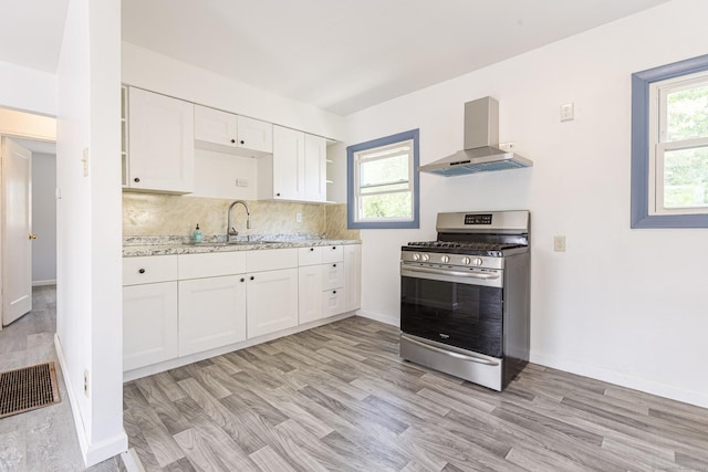 47 Manwaring Rd, Norwich, CT 06360 - kitchen featuring wall chimney range hood, stainless steel range with gas stovetop, white cabinetry, backsplash, and open shelves